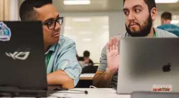 Two hackers talking in front of laptops